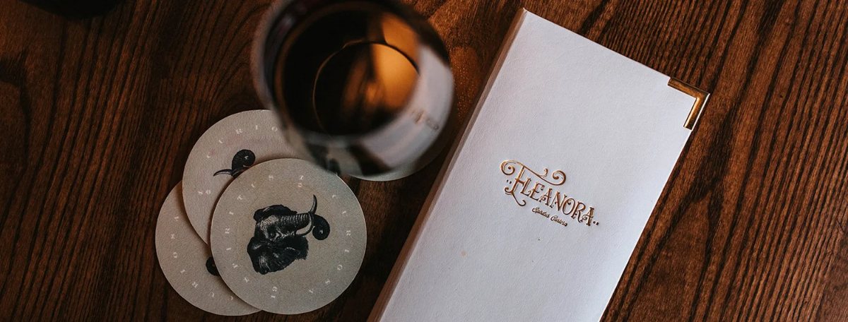 Eleanora box, coasters, and a drink on a wooden table
