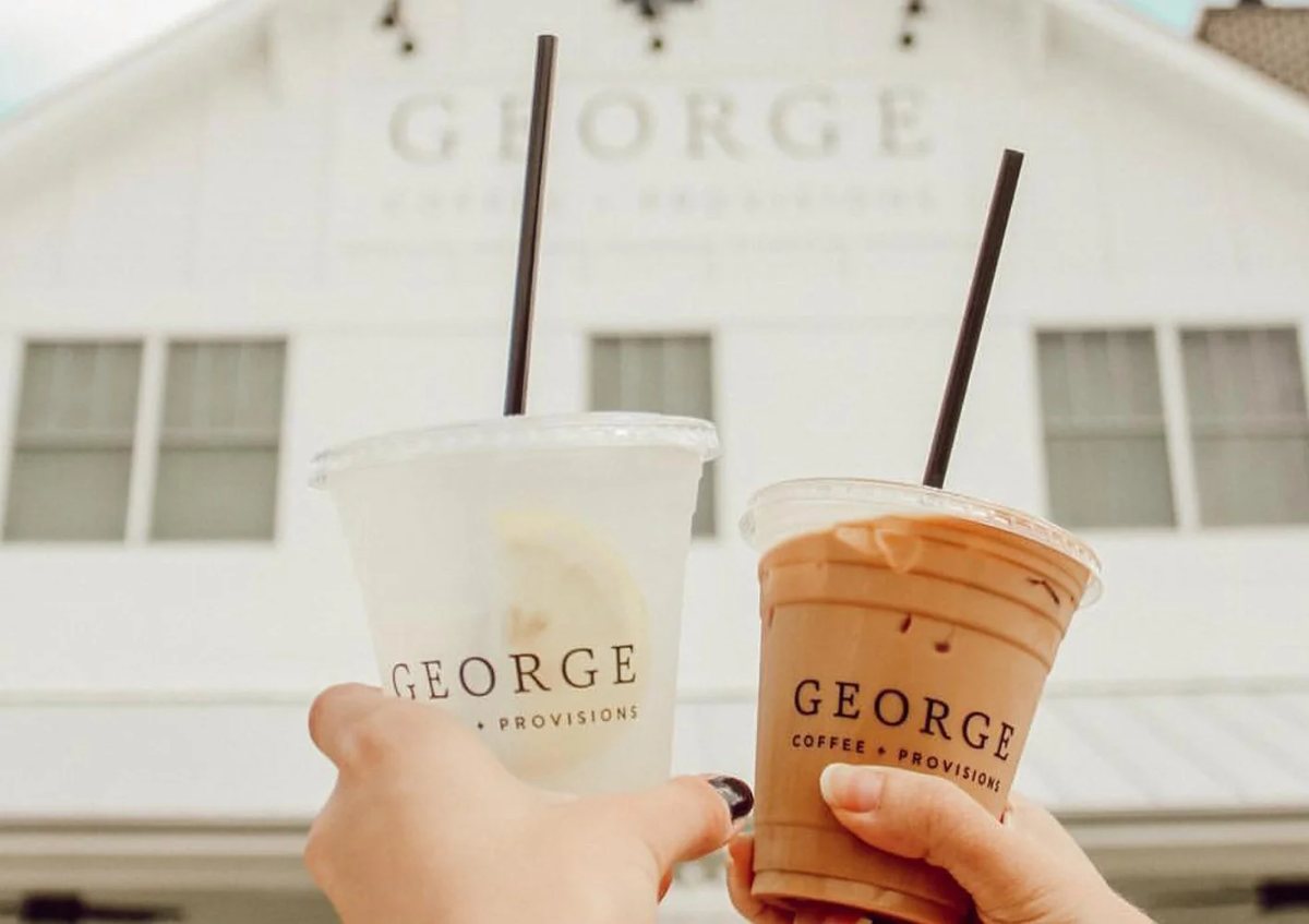 Two George Coffee drinks held up outside the shop