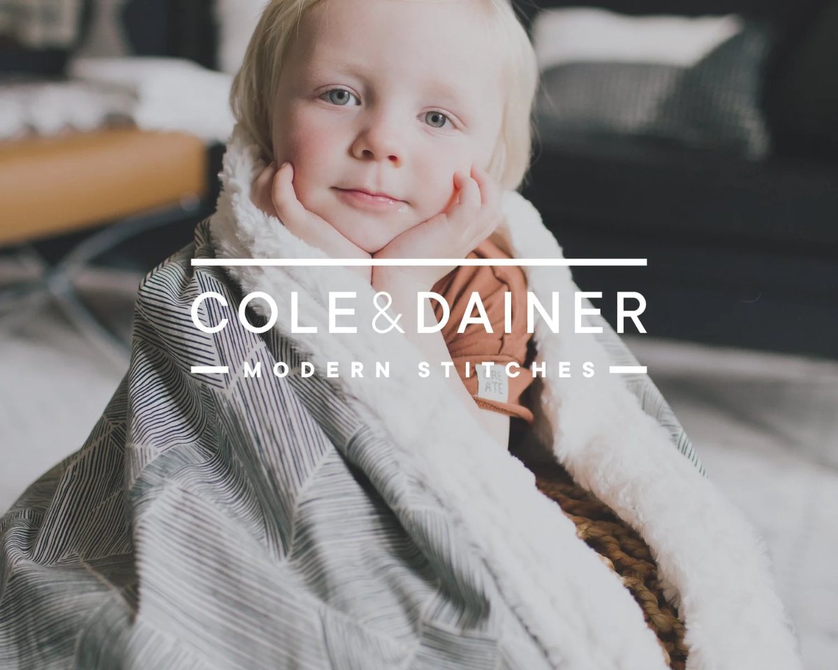 Cole and Dainer wordmark over a child wrapped in a blanket